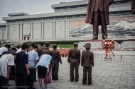 在金日成和金正日的雕像前，有源源不断的朝鲜民众带来鲜花，鞠躬行礼。游客在拍摄雕像，像这样只露出雕像的一部分是不允许的。