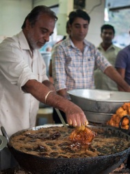 2013年12月16日，印度新德里，65岁的厨师有一项特殊的本领，就是徒手在滚烫的油锅中炸鱼。并且徒手从滚油中捞出炸鱼，丝毫不被烧伤。他的特殊技艺吸引众多民众围观。 