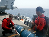 图为5月15日，美国海军技术人员正在“亚伯拉罕·林肯”号航母上检查一枚炸弹。 