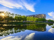 蓝天白云，阳光下的中国国家体育场——鸟巢倒映在水中如画 