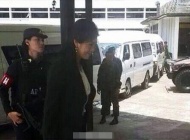 泰国发生军事政变后5月23日，泰国前总理英拉面带微笑在手持乌兹冲锋枪的女军人押送下进入“军事维安委员会”报告