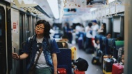 图为一位来自中国的游客，留着长发，手扶列车把手。