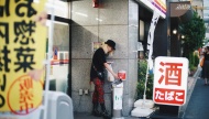 日本711门口的吸烟区，一位染发女子在抽烟。