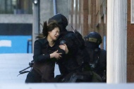 A hostage runs toward a police officer outside Lindt Chocolate Café, where other hostages are being held, in Martin Place in Sydney on Monday.