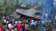 People gather around a downed aircraft in Athurugiriya, Sri Lanka, as firefighters try to extinguish flames amid the debris on Friday, December 12. The Sri Lanka Air Force plane crashed into a rubber plantation, killing all four people on board, police said.