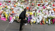 A man places flowers to pay his respects to the victims of the cafe siege in Sydney on Tuesday, December 16.