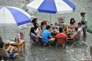 蓝白大伞下，游客们双足泡水，惬意搓麻。