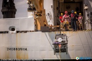 工作人员正在将潜水探测器从船只上逐渐地放入水中。